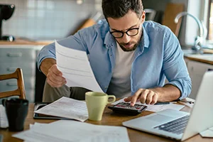 Person berechnet Finanzen mit Taschenrechner